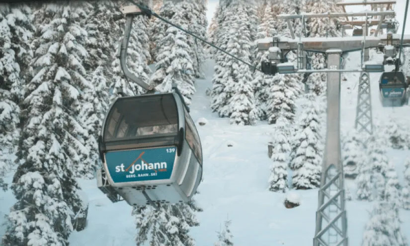 Cable car in St. Johann, snow and trees in the background