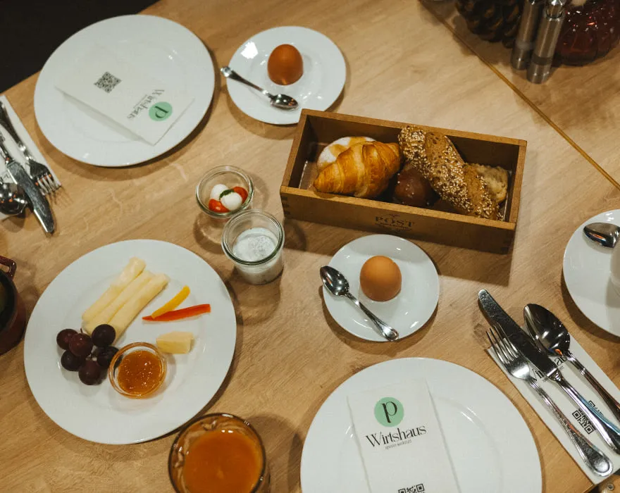 Frühstückstisch mit Brötchen, Obst, Joghurt und Eiern