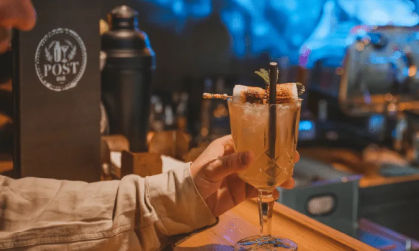 Drink on a bar with hand in the foreground
