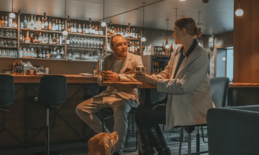 Couple conversing at a bar with a dog nearby