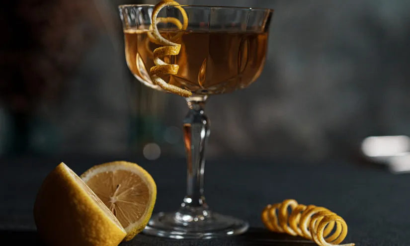 Cocktail in a glass with lemon twist and slice