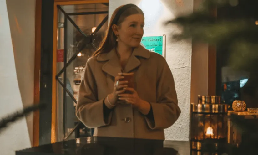Woman holding a cup in a busy indoor setting.